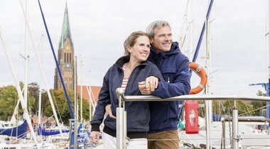 Personen auf dem Bootssteg im Schleswiger Stadthafen mit Blick auf Schleswiger Dom.