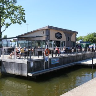 Blick auf das Hafencafé mit Außensitzplätzen am Schleswiger Stadthafen.