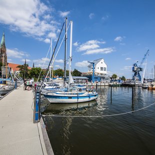 Sportboote liegen an einem Steg am Schleswiger Stadthafen.
