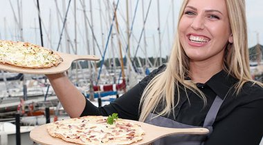 Perosn mit Speisen der Gastronomie am Schleswiger Stadthafen.